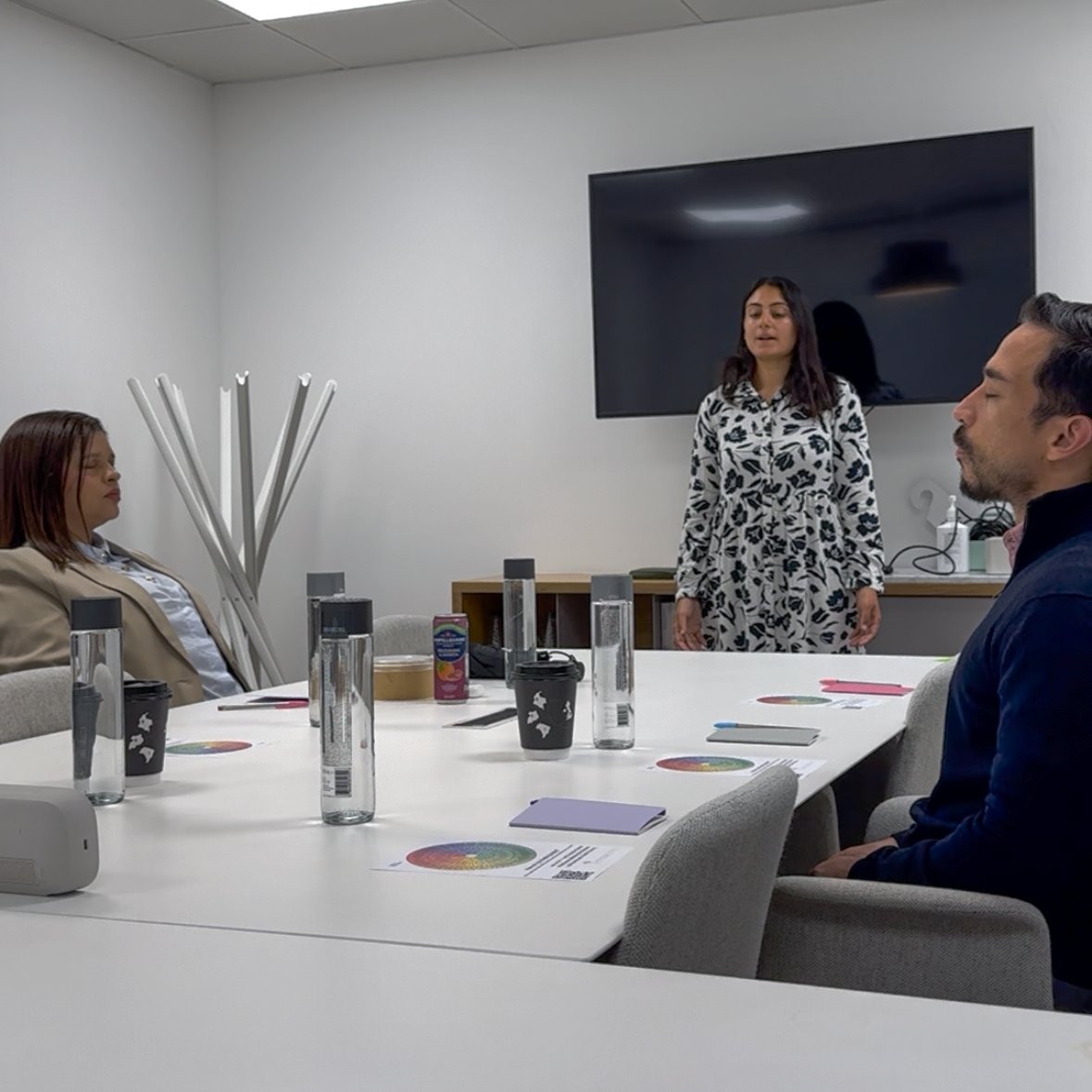 Team members taking part in a guided mindfulness session around a meeting table